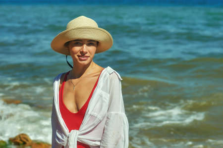 Portrait of a young woman on the sea coast. Beautiful woman in a straw hat by the sea.の写真素材