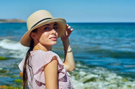 Portrait of a young woman in a straw hat on the sea coastの写真素材