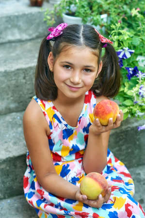 Portrait of a happy little girl with peachesの写真素材