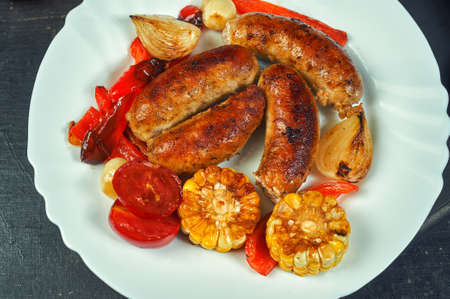 fried homemade sausages with vegetables on a plate .cooking at home. the view from the topの写真素材
