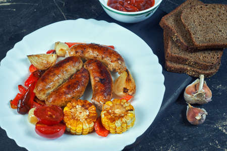 fried homemade sausages with vegetables on a plate .cooking at home. the view from the topの写真素材