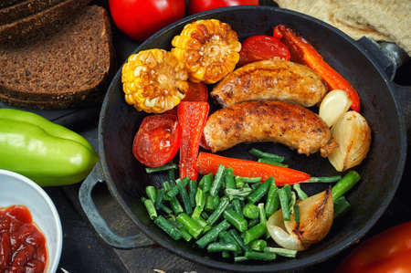 fried homemade sausages with vegetables in a pan .cooking at homeの写真素材