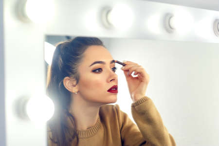 A young beautiful woman makes her own makeup at home .My own makeup artistの写真素材