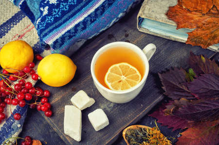 a Cup of hot green tea on a dark background with lemons and berries.の写真素材