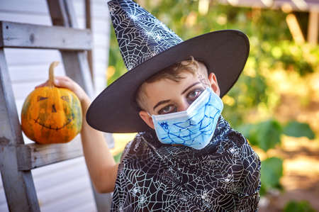 Portrait of a boy in a carnival costume for Halloween. Children wearing masks to protect against COVID-19.の写真素材