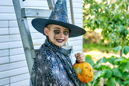 Portrait of a boy in a carnival costume with a pumpkin on Halloweenの写真素材