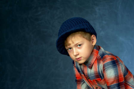 Portrait of a boy in a knitted hat in the Studio on a dark background.