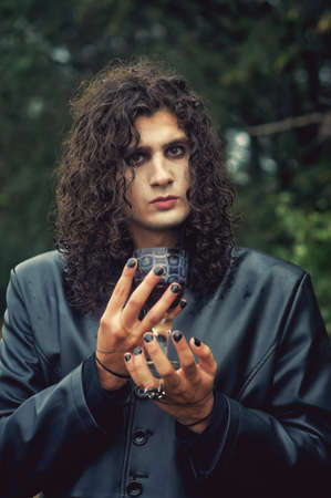 Stylish man with dark curly hair in a leather coat. Gothic style.の写真素材