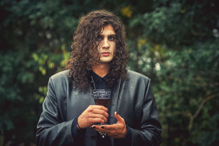Stylish man with dark curly hair in a leather coat. Gothic style.の写真素材