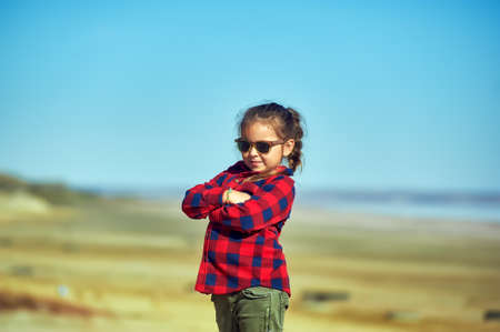 Portrait of a little girl in nature. The child wears a comfortable shirt and jeans. The concept of casual wearの写真素材