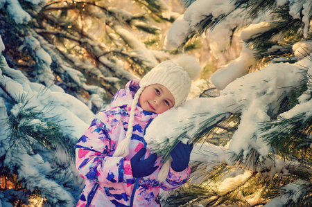 Portrait of a happy little girl on a winter walk. A child in comfortable clothes in the forestの写真素材