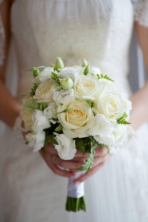 bridal bouquet of white roses in hands of the brideの写真素材
