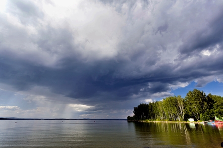 dark storm clouds before rain above the lake, the calm before the stormの写真素材