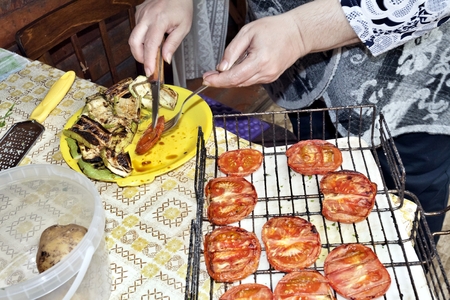 grilled tomatoes spread on a plate, the hands of the cook are visibleの写真素材