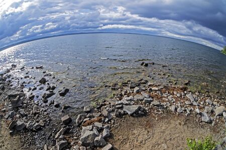 rocky shore of the morning lake in cloudy weather in the southern Urals, lake Uvildy, filmed lens...