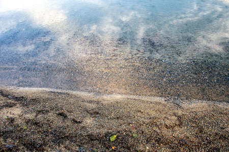 coastal sand and calm lake water, visible sand texture