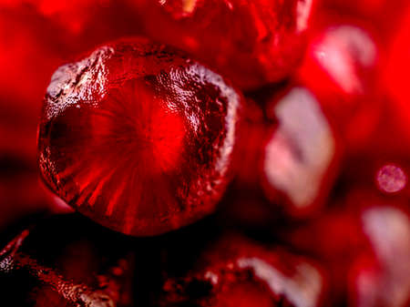 slice the pomegranate with red grains on a black background, a narrow focus area, surface texture of pomegranate seeds is visibleの写真素材