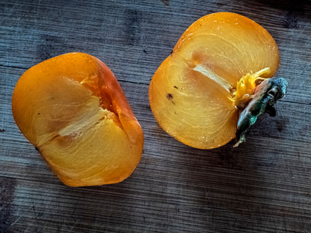 ripe fresh orange persimmon fruit on a wooden Board cut in half