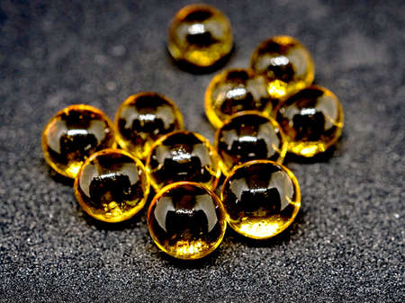 yellow round transparent gelatin capsules on a black background