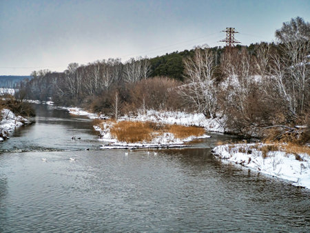 view from the bridge on the Miass River in winter outside the city during a heavy snowfall, open...