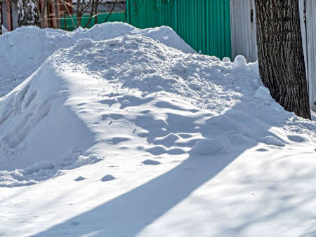 snowdrift and clumps of snow near the fenceの写真素材