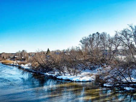 view from the bridge to the river in the spring outside the city in the evening, the sun shines, snow melts, pine forest, countryside, Miass River near the village of Kashtak, Southern Uralsの写真素材