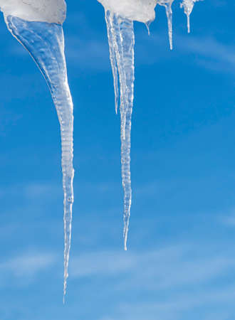 transparent icicles of ice against the blue skyの写真素材