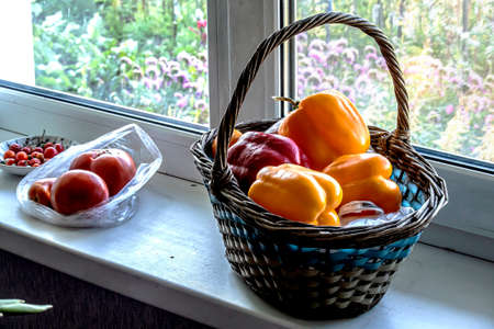 fresh ripe multicolored peppers in a basket on the windowsillの写真素材