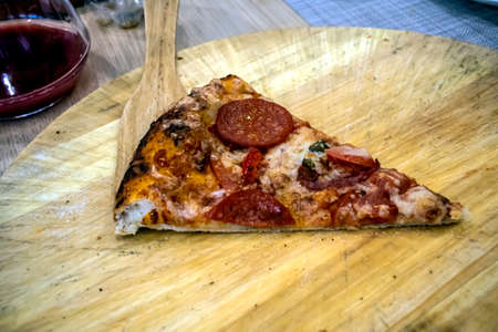 fresh pizza on the table on a wooden platterの写真素材