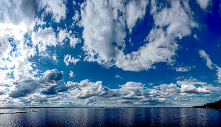 panorama blue sky with white and gray cumulus clouds over morning lake, southern Urals, Lake Uvildyの写真素材