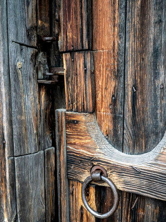 old iron handle in the form of a ring on the wooden door of the entrance to the village old house, old Russian village lifeの写真素材