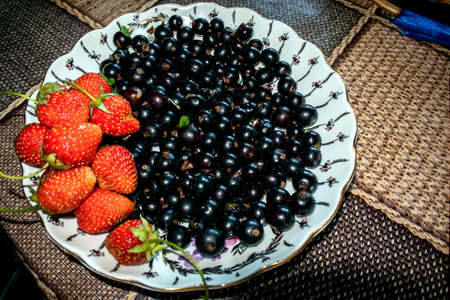 a plate with fresh black currant and red Victoria berriesの写真素材