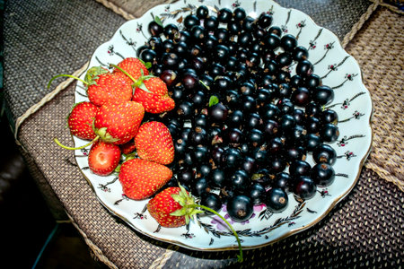 a plate with fresh black currant and red Victoria berriesの写真素材