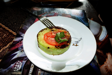 Fried zucchini slices with crispy crust, tomatoes, herbs and garlic, a delicious dishの写真素材