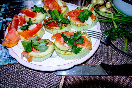 Fried zucchini slices with crispy crust, tomatoes, herbs and garlicの写真素材