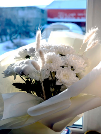 bouquet of white chrysanthemums combined with cotton flowers on the windowsillの写真素材