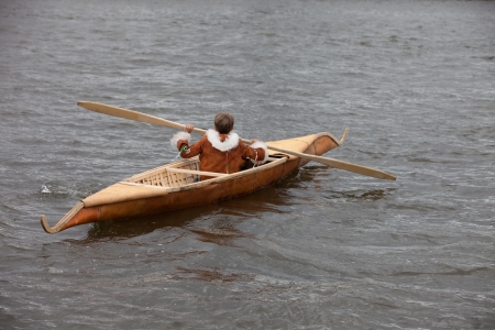 traditional boat of Siberia with the fisherman in national dressの写真素材