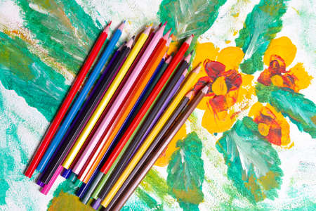scattered colored pencils on a colorful sheetの写真素材