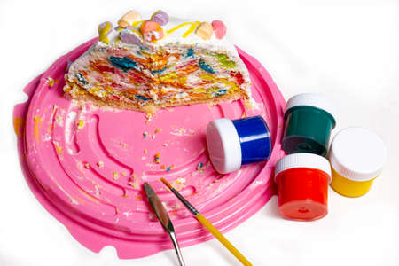 a piece of sponge colored cake on the table with jars of colorful paintの写真素材