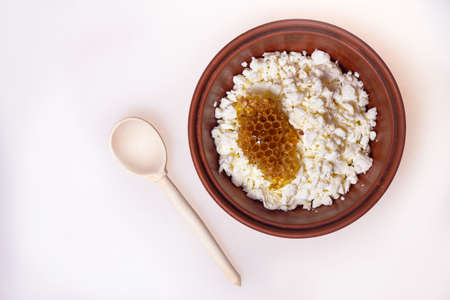 cottage cheese with honeycomb in a bowl on a table with a wooden spoonの写真素材