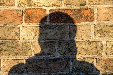Man shadow on a brick wall backgroundの写真素材