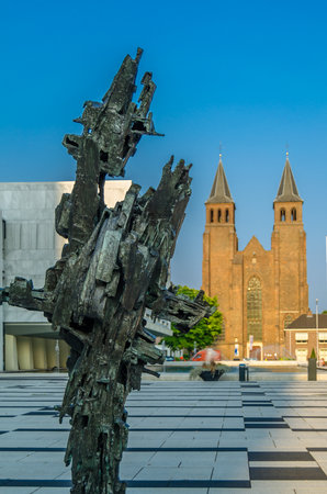 ARNHEM, THE NETHERLANDS - AUGUST 23, 2013: Urban scene, view of the modern sculpture âEvolutionâ, by Piet Slegers from 1969 in front of the town hall and the the St. Walburgis Church in the backgroundのeditorial素材