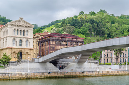 BILBAO, SPAIN - MAY 10, 2014: The Pedro Arrupe pedestrian walkway over the Nervion River in Bilbao, Basque Country, Spain, with the University of Deusto in the backgroundのeditorial素材