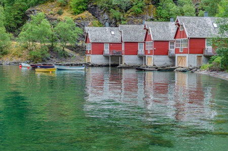 FLAM, NORWAY - JULY 16, 2014: View of rustic red painted wooden houses on the shore of Aurlandsfjord, in the village of Flam, Vestland county, Norwayのeditorial素材