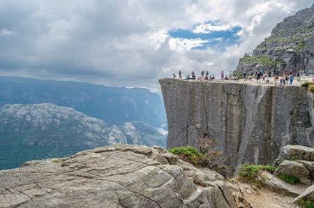 STRAND, NORWAY - JULY 14, 2014: People on the platform of Preikestolen (The Pulpit Rock), a tourist attraction in Rogaland county, Norway, a steep cliff which rises 604 meters above the Lysefjordenのeditorial素材