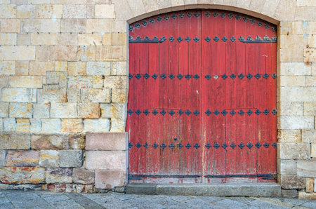 Architectural detail of a red wooden door and a stone wallの写真素材