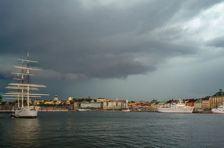 STOCKHOLM, SWEDEN - JULY 27, 2014: View of Stockholm, Sweden, with storm clouds. In the foreground "af Chapman", a full-rigged steel ship moored on the Skeppsholmen islet, now serving as a youth hostelのeditorial素材