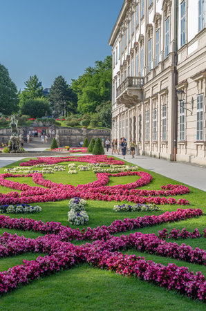 SALZBURG, AUSTRIA - JULY 5, 2015: People strolling through the Mirabell Palace and Mirabell Gardens (Mirabellgarten), a formal baroque-style public garden with geometric flowerbeds in Salzburg, Austria
