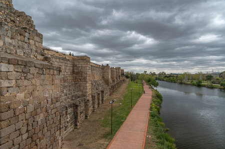 MERIDA, SPAIN - APRIL 1, 2023: Alcazaba of Merida, historic fortress on the bank of the Guadiana River, with people visiting and walking along the riverside. Built in 835 in the emiral Andalusi period near the Roman Bridge, it reused Roman and Visigoth maのeditorial素材