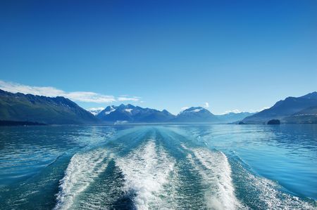 Waves from the boat and deep blue sky under the mountain of Alaskaの写真素材